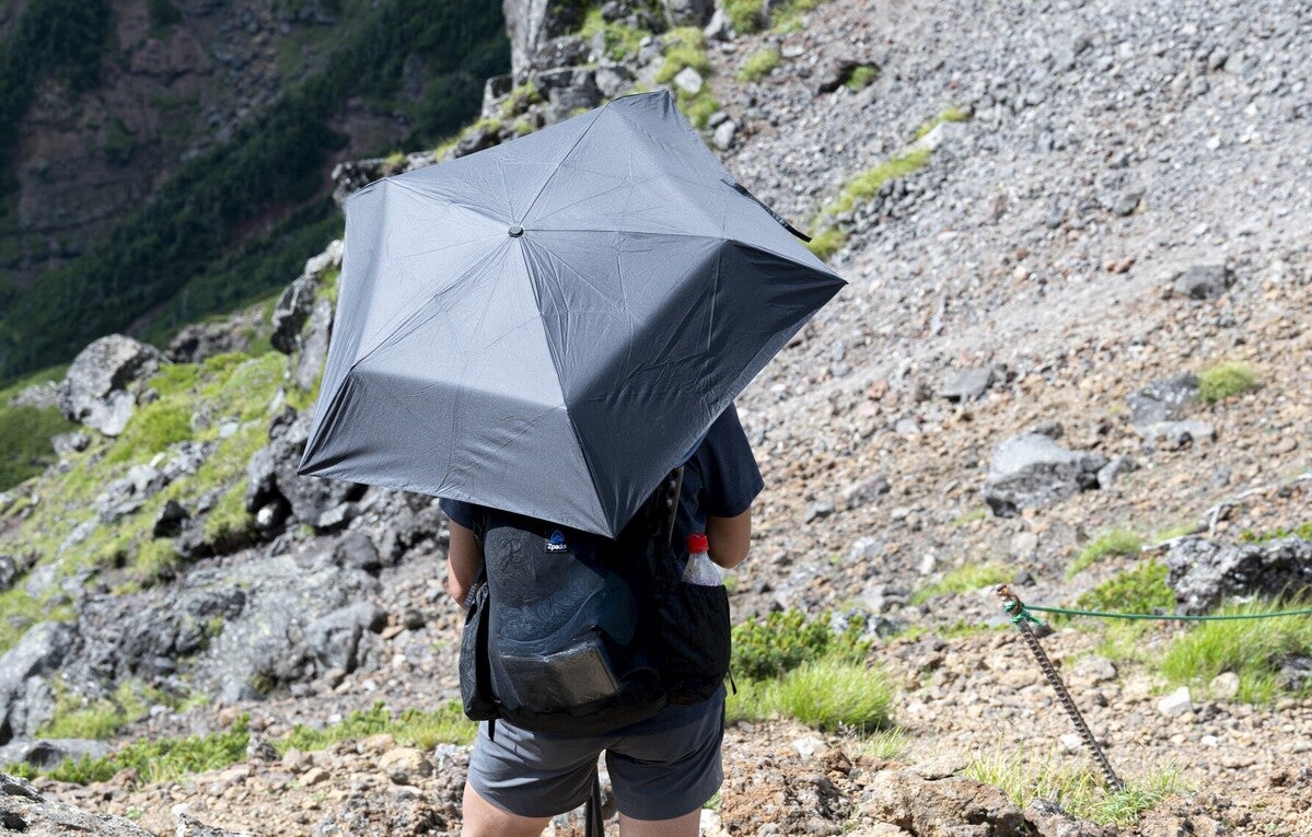 登山中に日傘をさす男性の後ろ姿